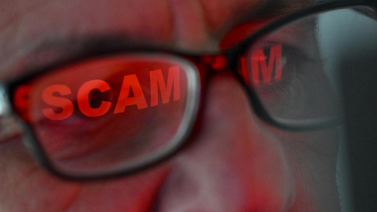 The word 'scam' is seen reflected in a person's glasses (file image)