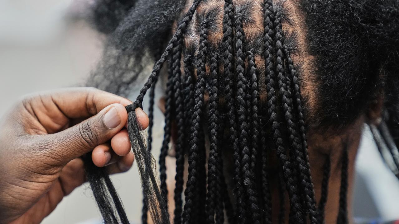 A stylist uses synthetic hair to braid