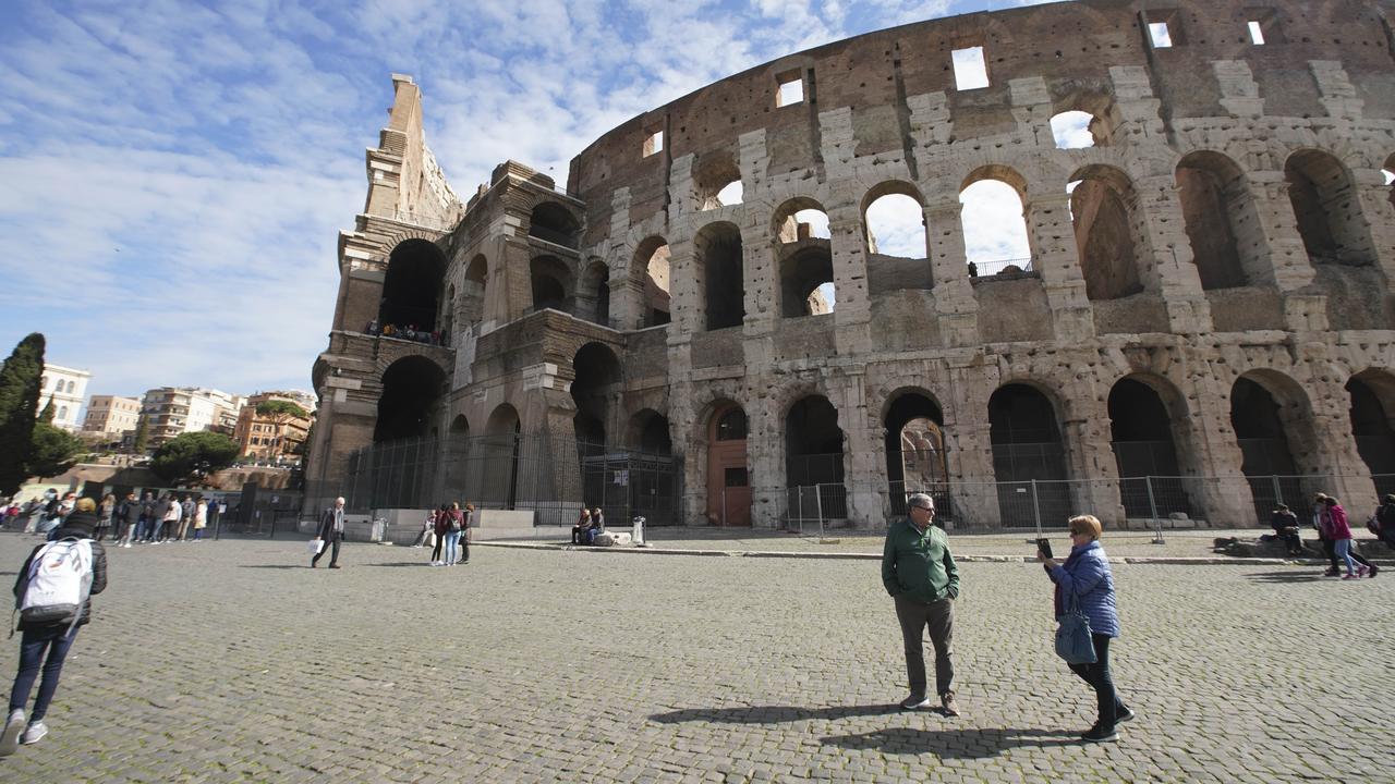 People walk by the Colosseum in Rome