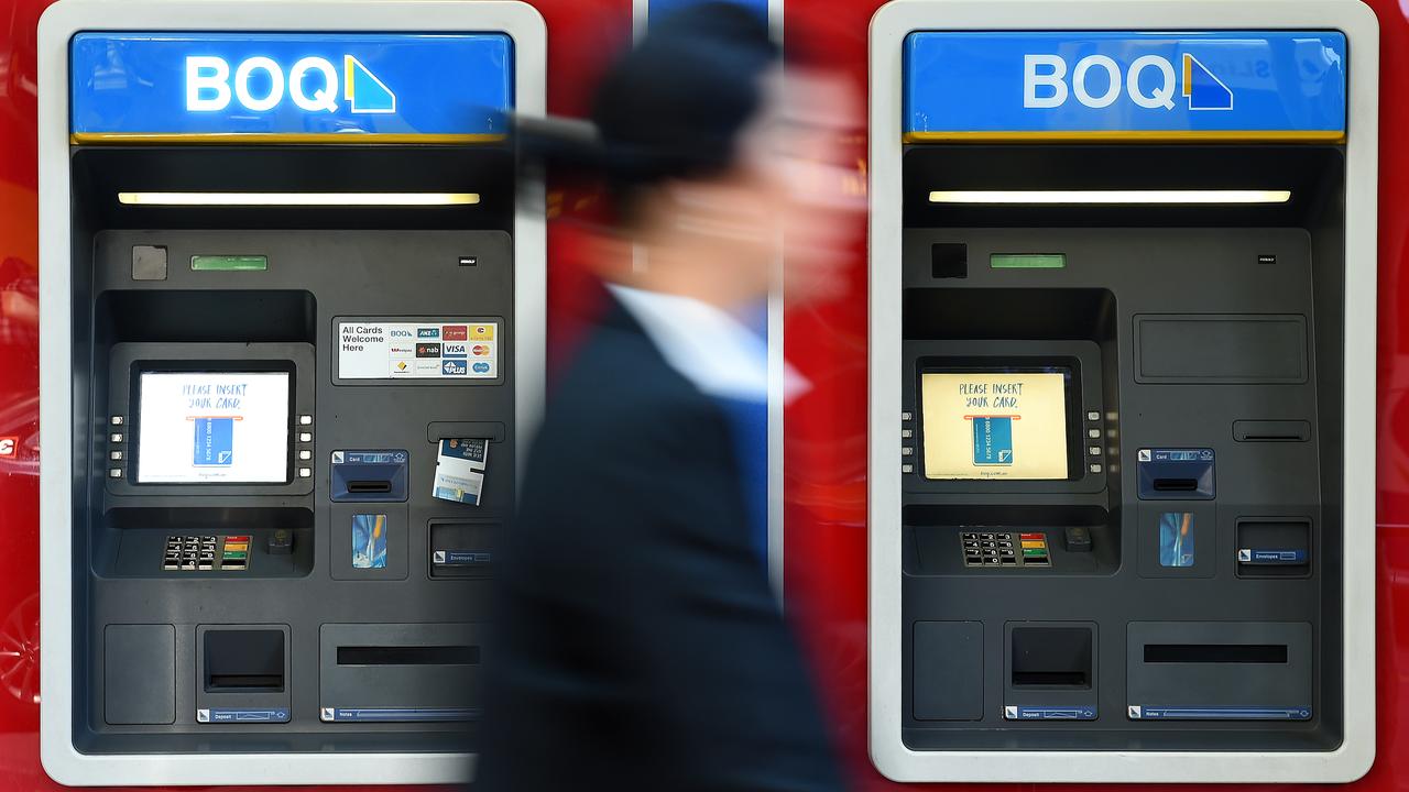 A person walks past Bank of Queensland ATMS