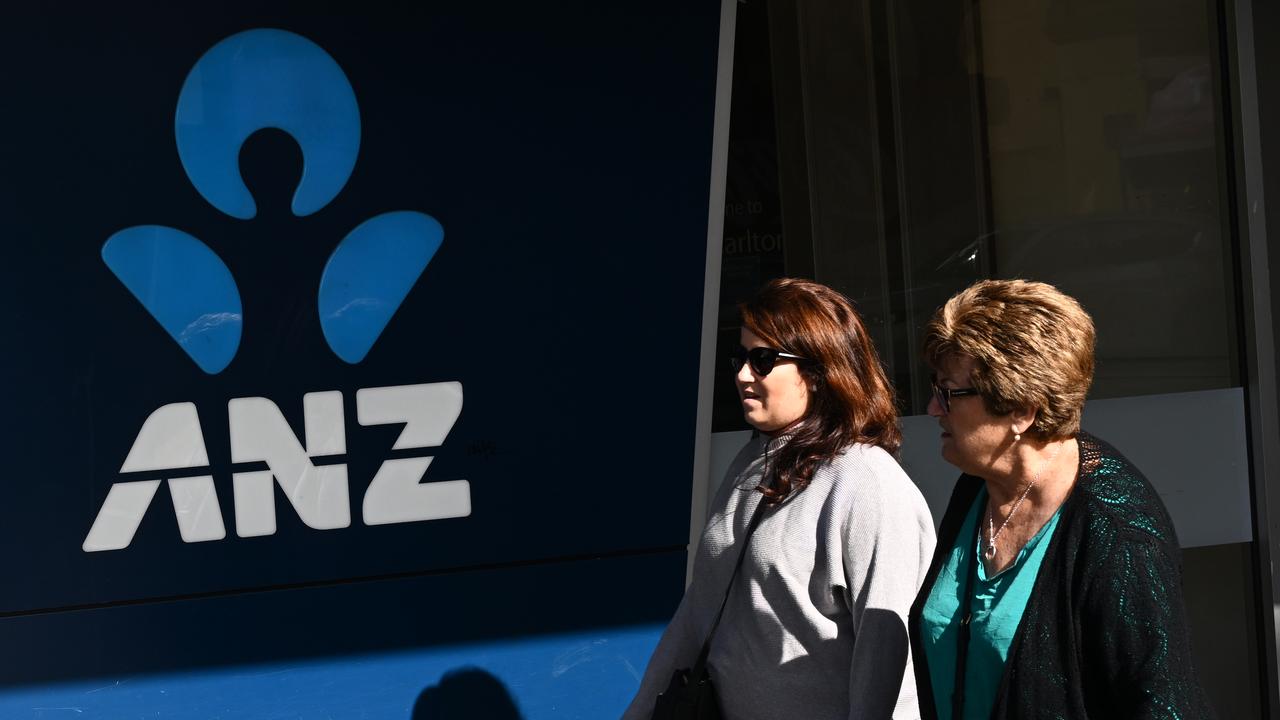 People walk past the ANZ logo