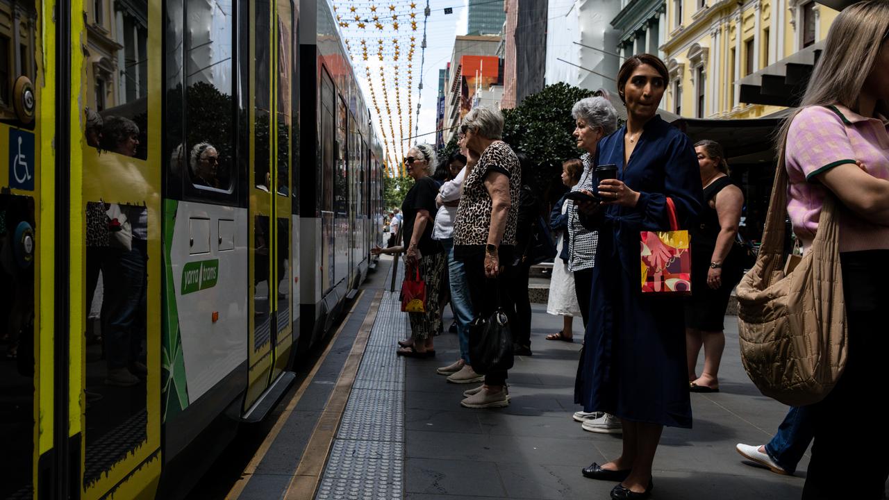 People wait at a tram stop along Bourke Street Mall