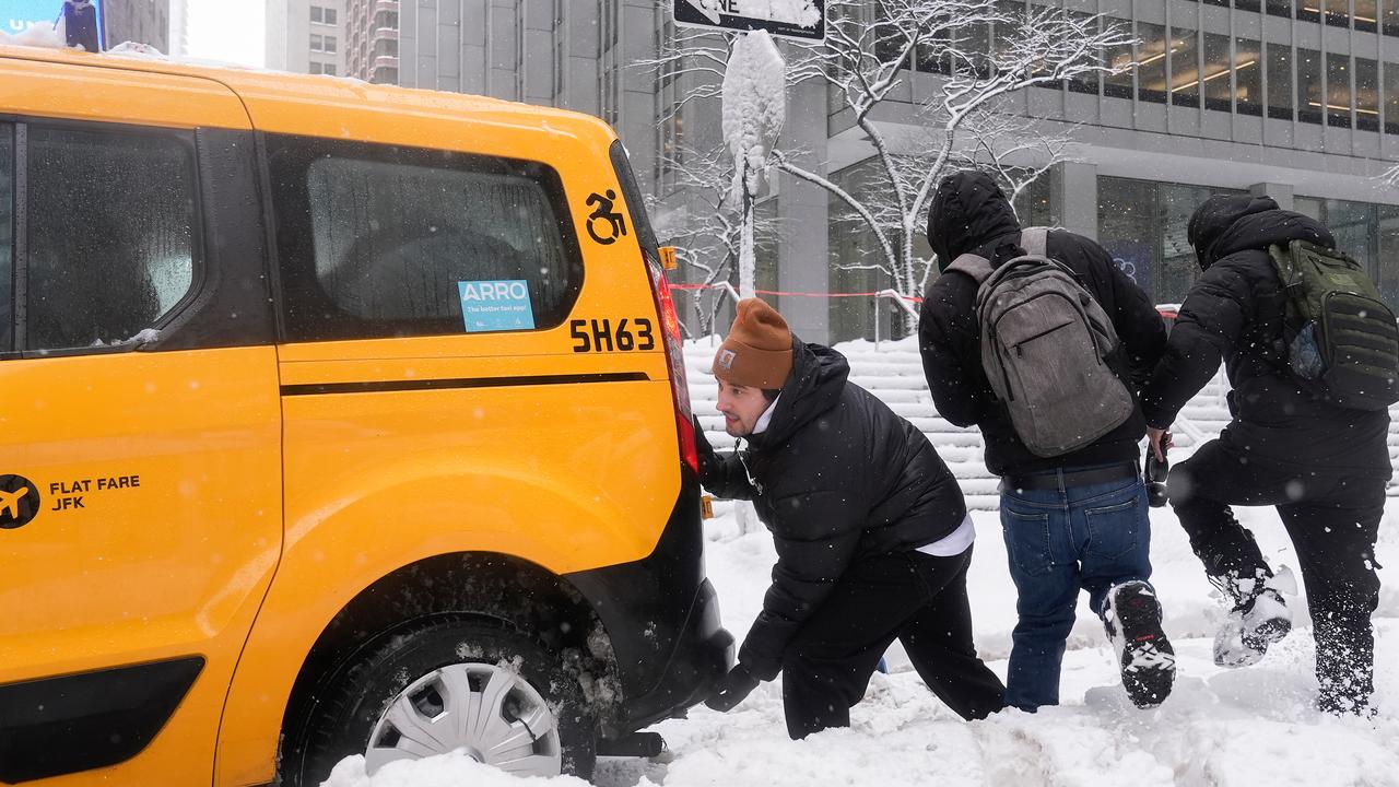 Men push a taxi stuck in the snow in NYC