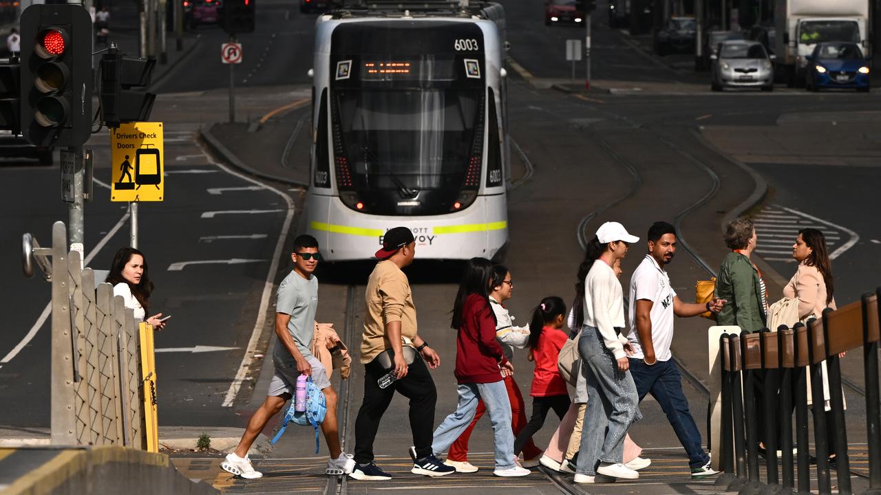 Pedestrians walk past the Yarra Tram