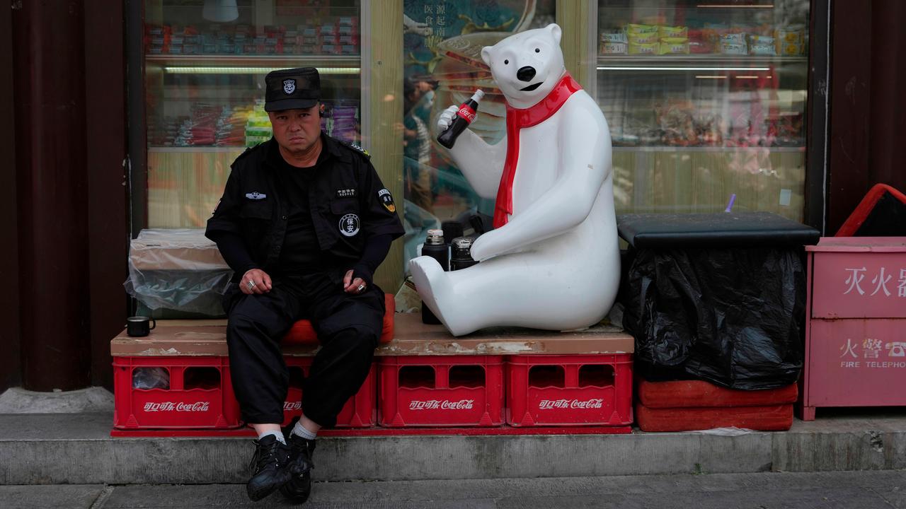 A security guard next to a Coca Cola mascot in Beijing