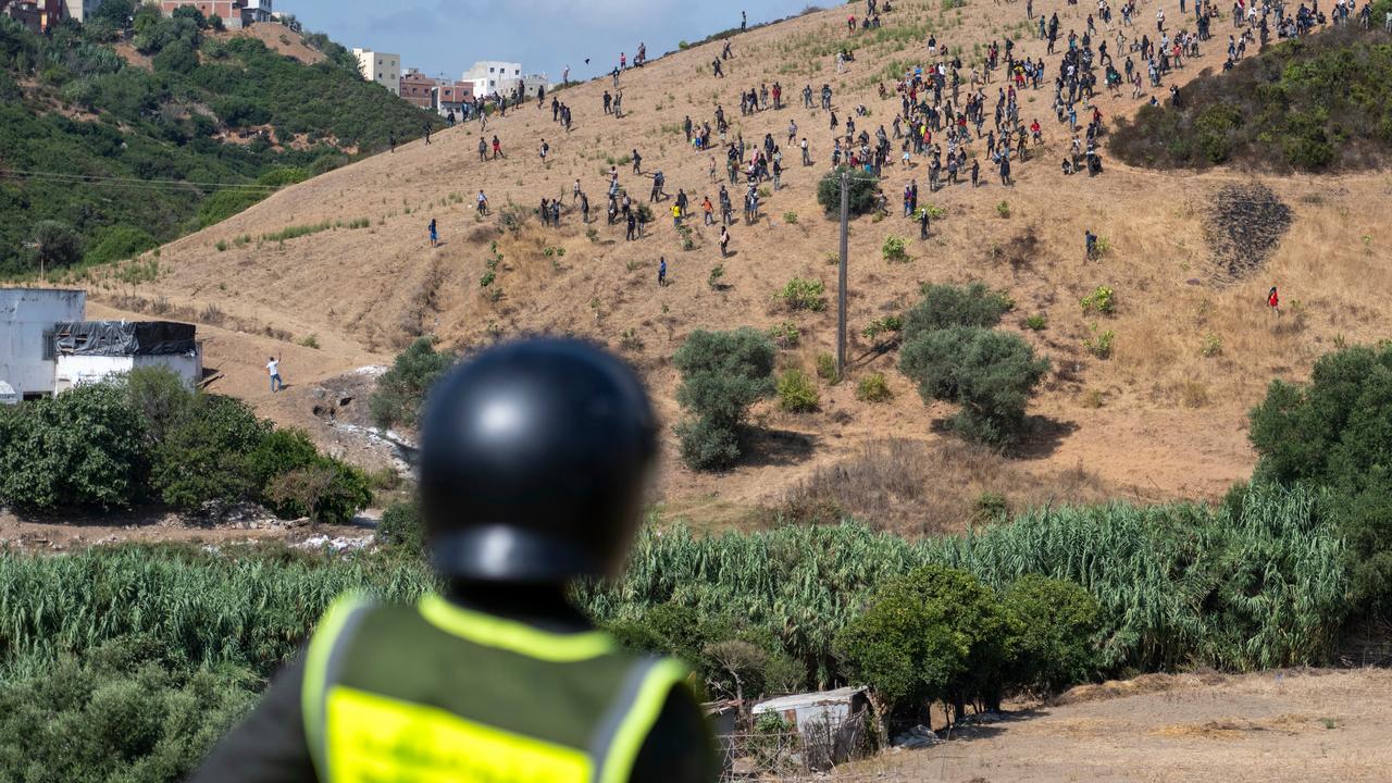 A guard watches migrants on a hill
