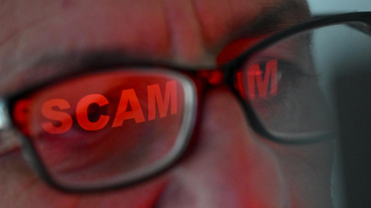 The word 'scam' reflected in a person's glasses (file image)