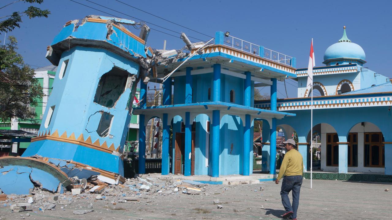 A man walks near a damaged mosque