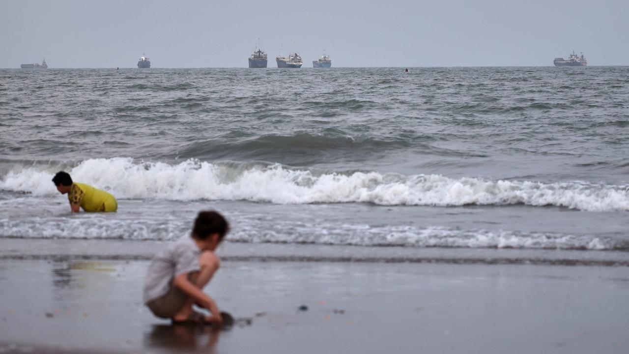 Children play at the beach with boats in the strait out at sea