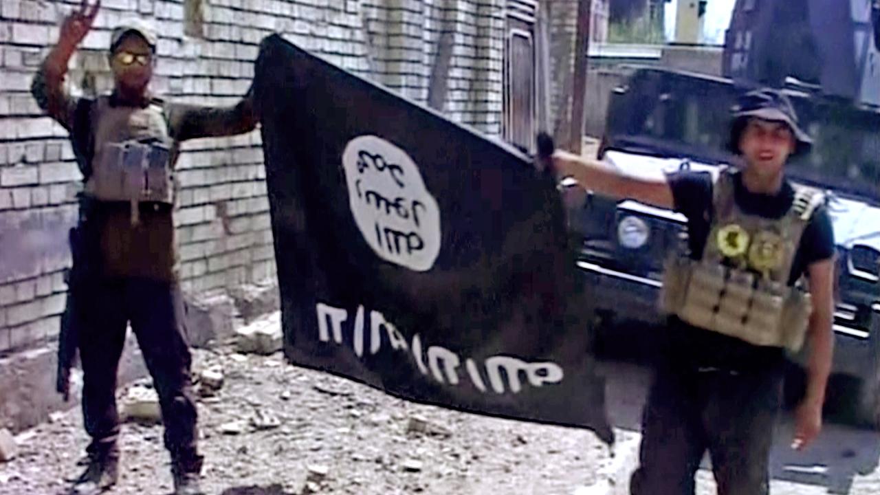 Two Iraqi soldiers holding an Islamic State flag upside down