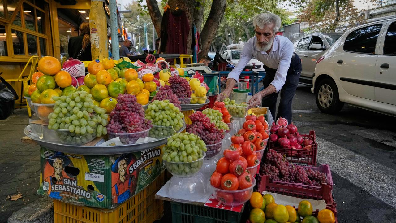 A shopkeeper arranges grapes