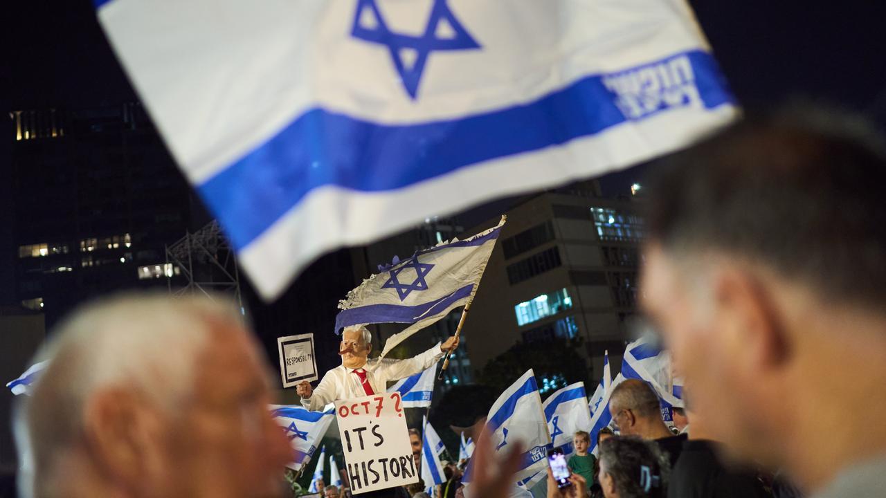 A demonstrator wears a mask depicting Benjamin Netanyahu